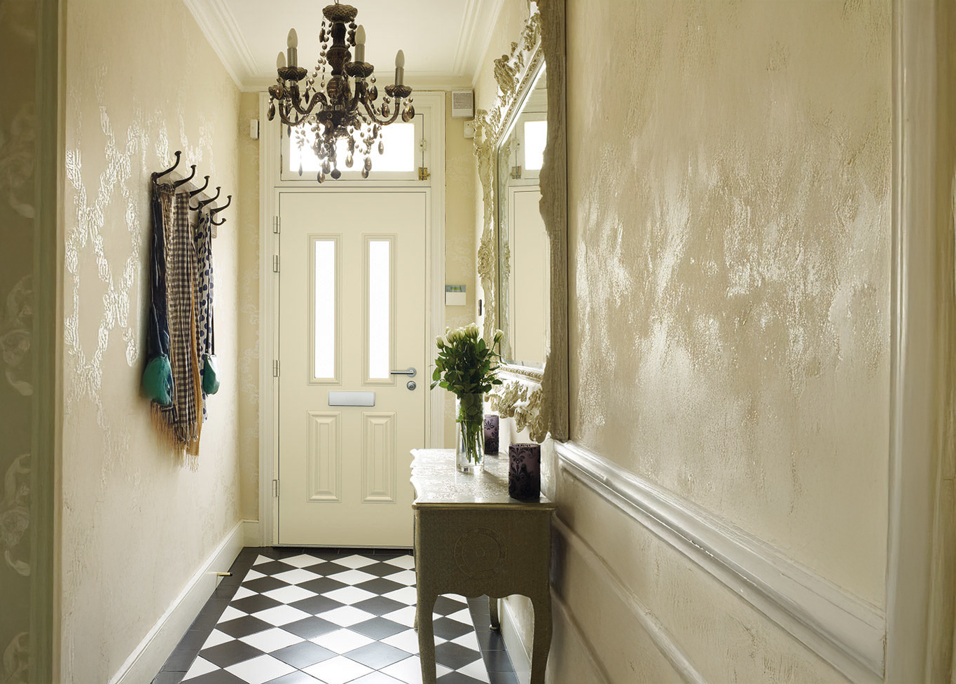 A hallway with a checkered floor and a chandelier hanging from the ceiling