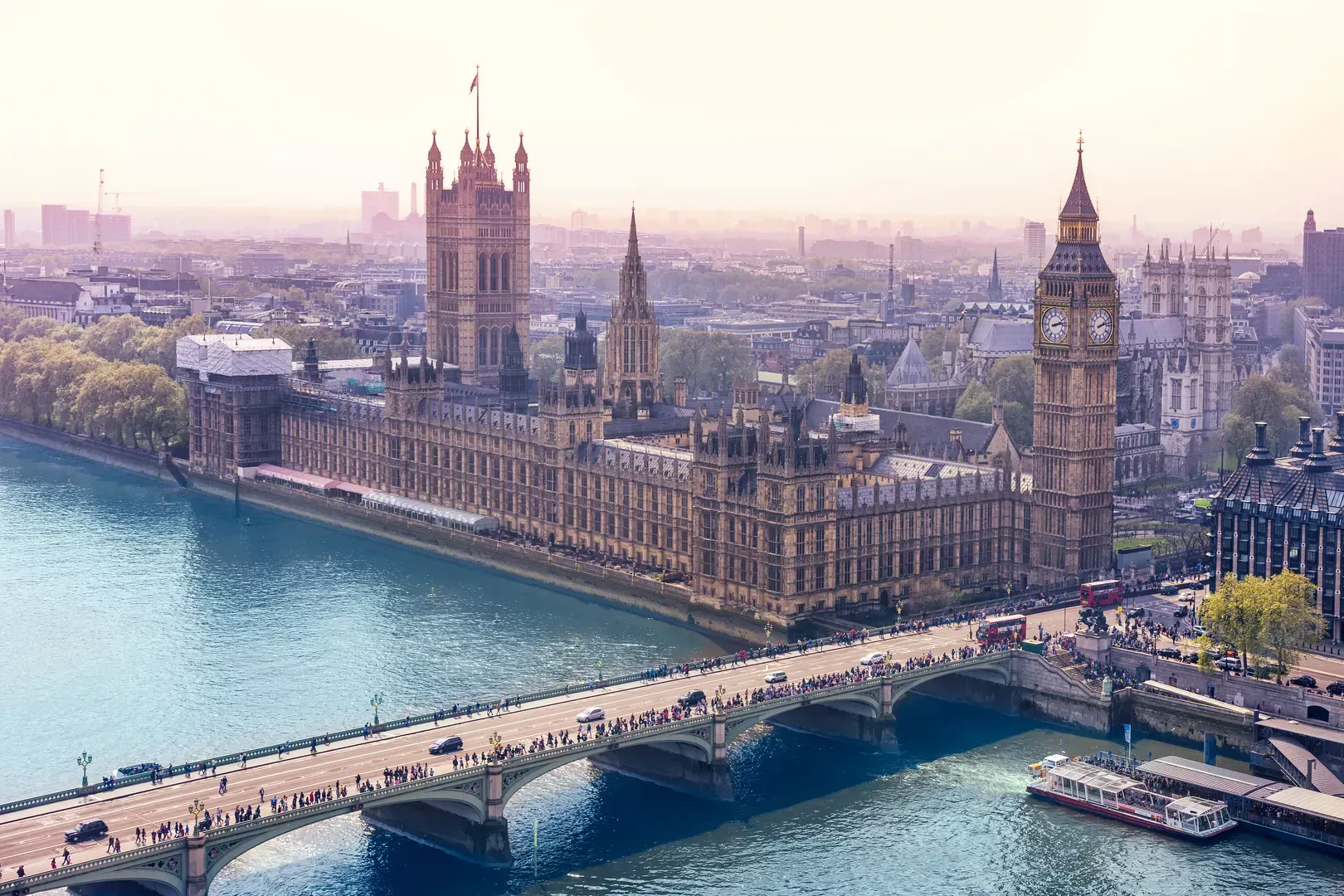 Die Houses of Parliament und Big Ben am Ufer der Themse, mit der Westminster Bridge im Sonnenuntergang.