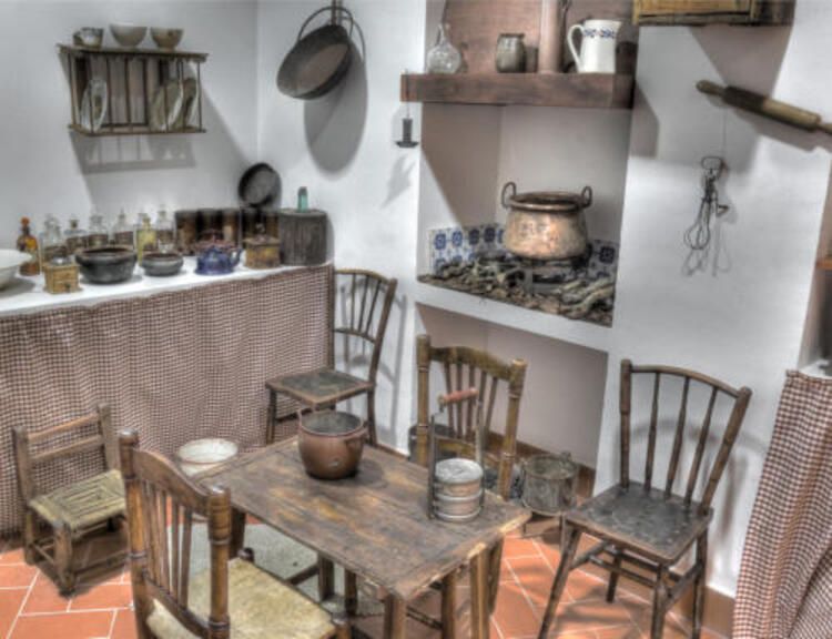 Una cocina con una mesa y sillas y ollas y sartenes en la pared.