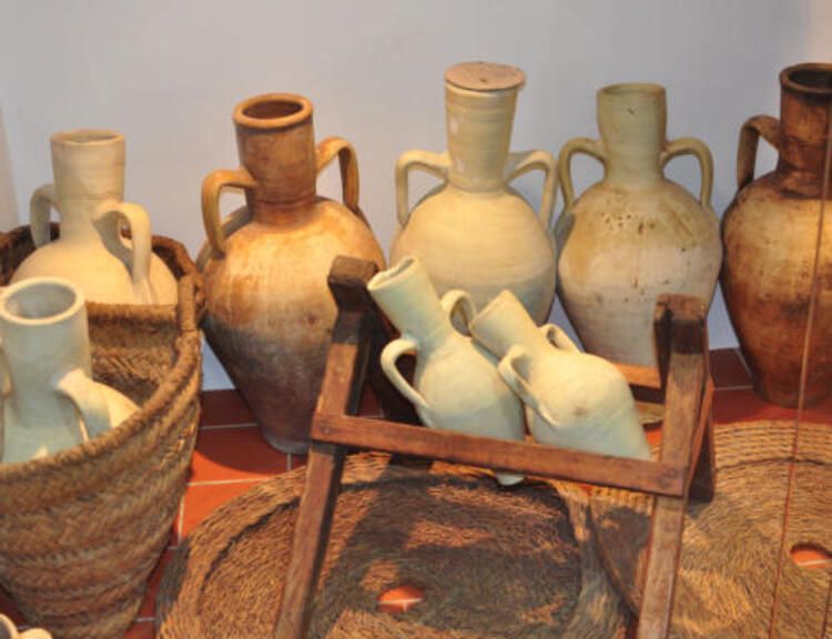 Una hilera de ollas y cestas de barro sobre una mesa.