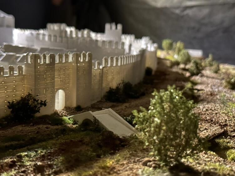 Un modelo de un castillo rodeado de árboles y arbustos sobre una mesa.