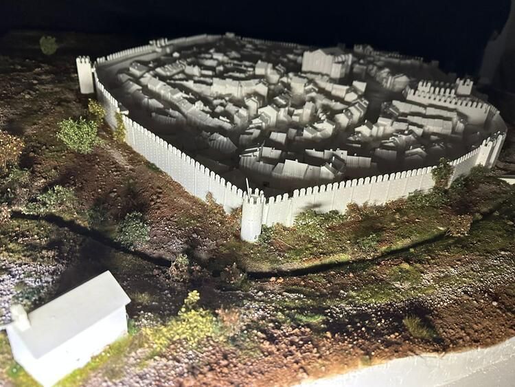 Una maqueta de un castillo con una casa blanca en primer plano.