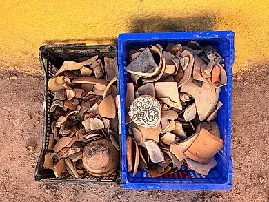 Dos cajas llenas de cerámica rota se encuentran una al lado de la otra en el suelo.