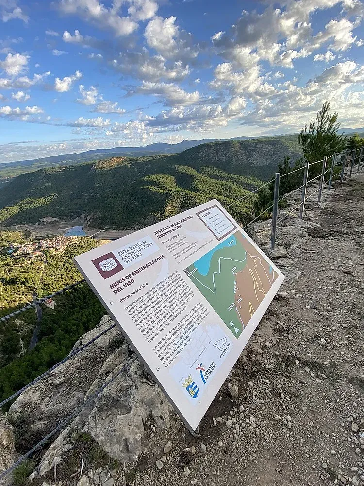 Un cartel se encuentra en la cima de una colina rocosa con vista a un valle.