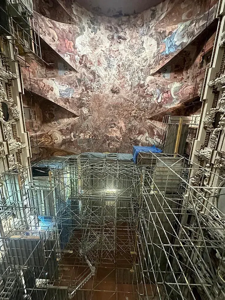 Una gran sala llena de andamios y una pintura en el techo.
