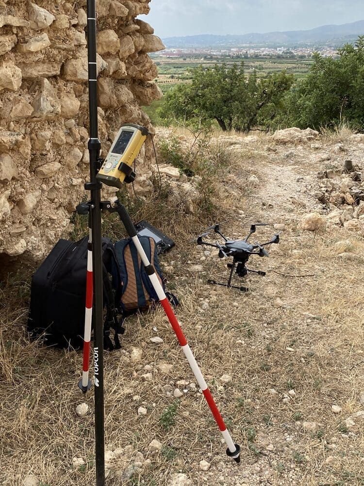 Un dron está sentado sobre un trípode al lado de un poste.