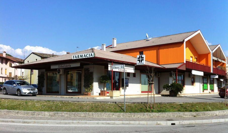 Farmacista sorridente, con in mano un blocco per appunti, in una corsia della farmacia, circondato da scaffali pieni di prodotti.