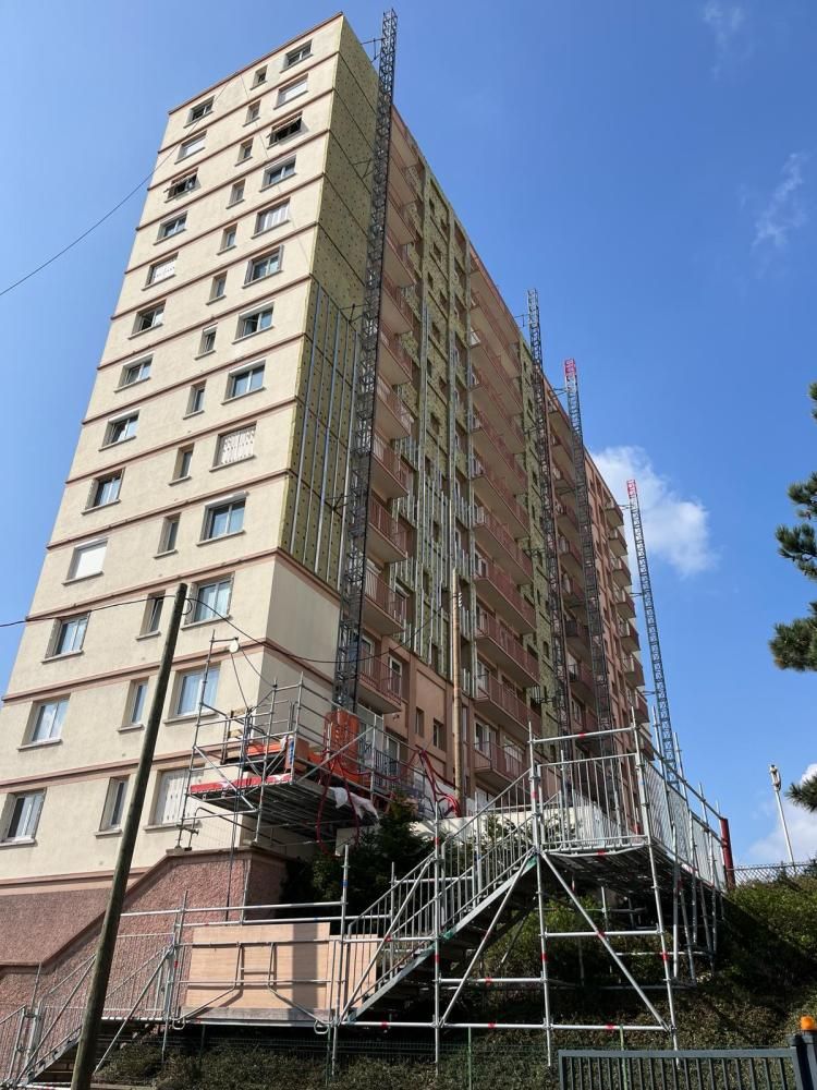 Immeuble d’habitation de grande hauteur avec des échafaudages et des travaux de construction sur fond de ciel bleu