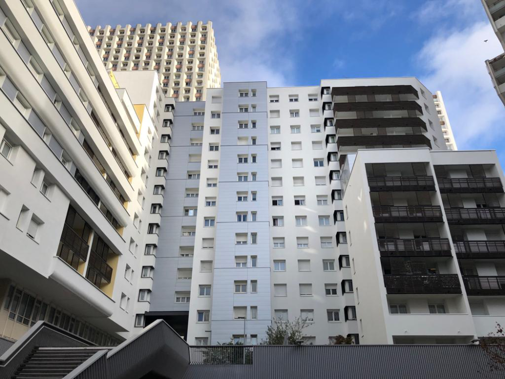 De grands immeubles résidentiels blancs avec des balcons, vus d’en bas sur fond de ciel bleu