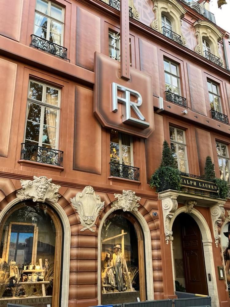 Boutique de luxe avec une façade en terre cuite, des fenêtres cintrées et une grande enseigne « PR » au-dessus de l’entrée