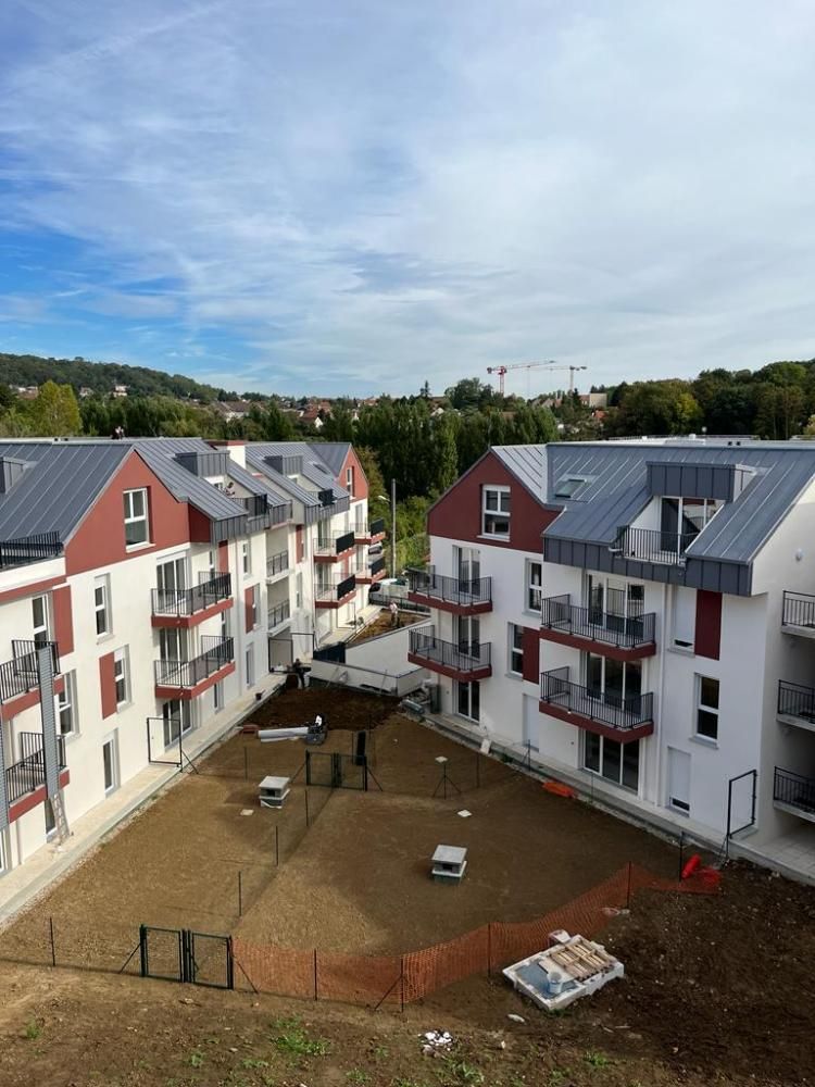 Cour intérieure entre des immeubles d’habitation rouges et blancs, sous un ciel nuageux
