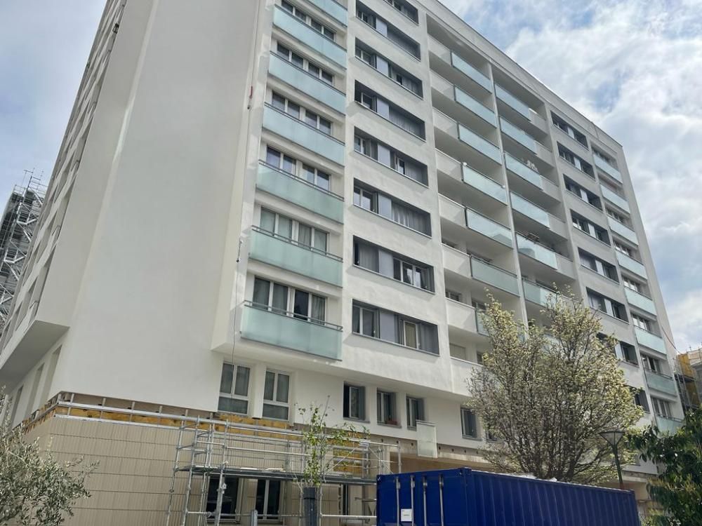 Immeuble résidentiel de faible hauteur avec des balcons et des arbres au niveau de la rue