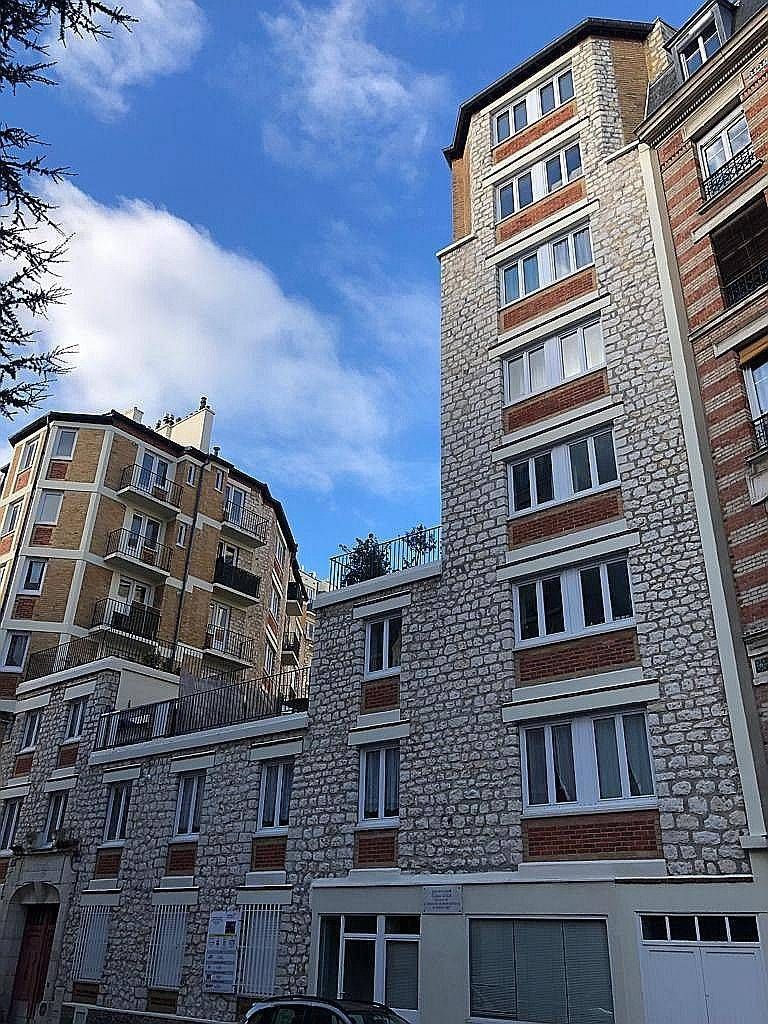 Immeubles en briques vus d’en bas sur fond de ciel bleu nuageux.