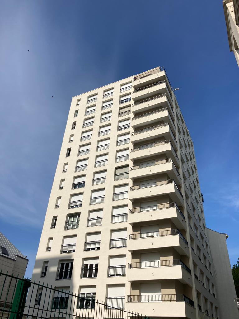 Grand immeuble d’habitation beige avec des balcons sur fond de ciel bleu