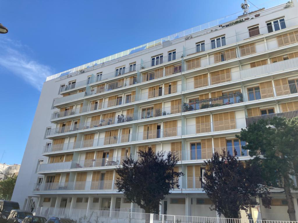 Immeuble résidentiel moderne blanc avec des balcons et des arbres sous un ciel bleu