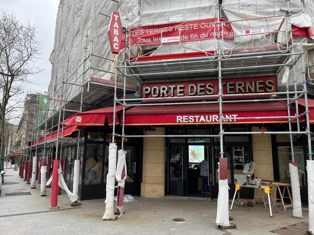 Façade de restaurant en rénovation, avec des auvents rouges et une enseigne portant l’inscription « Porte des Ternes », dans une rue animée