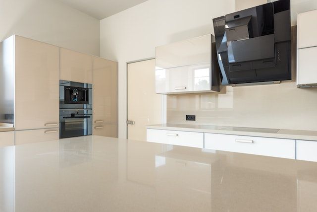 Una cocina vacía con gabinetes blancos y una campana extractora negra.