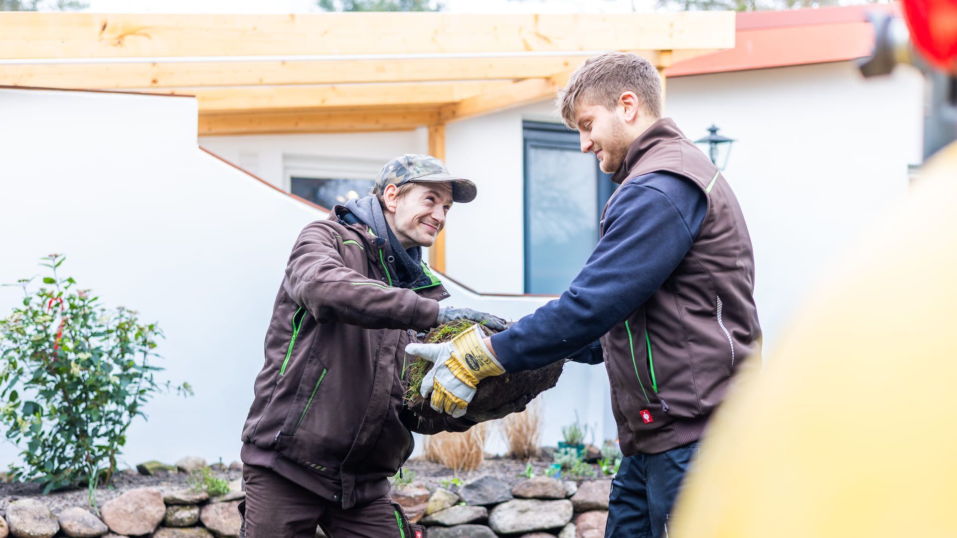 Zwei Männer schütteln sich vor einem Haus die Hand.