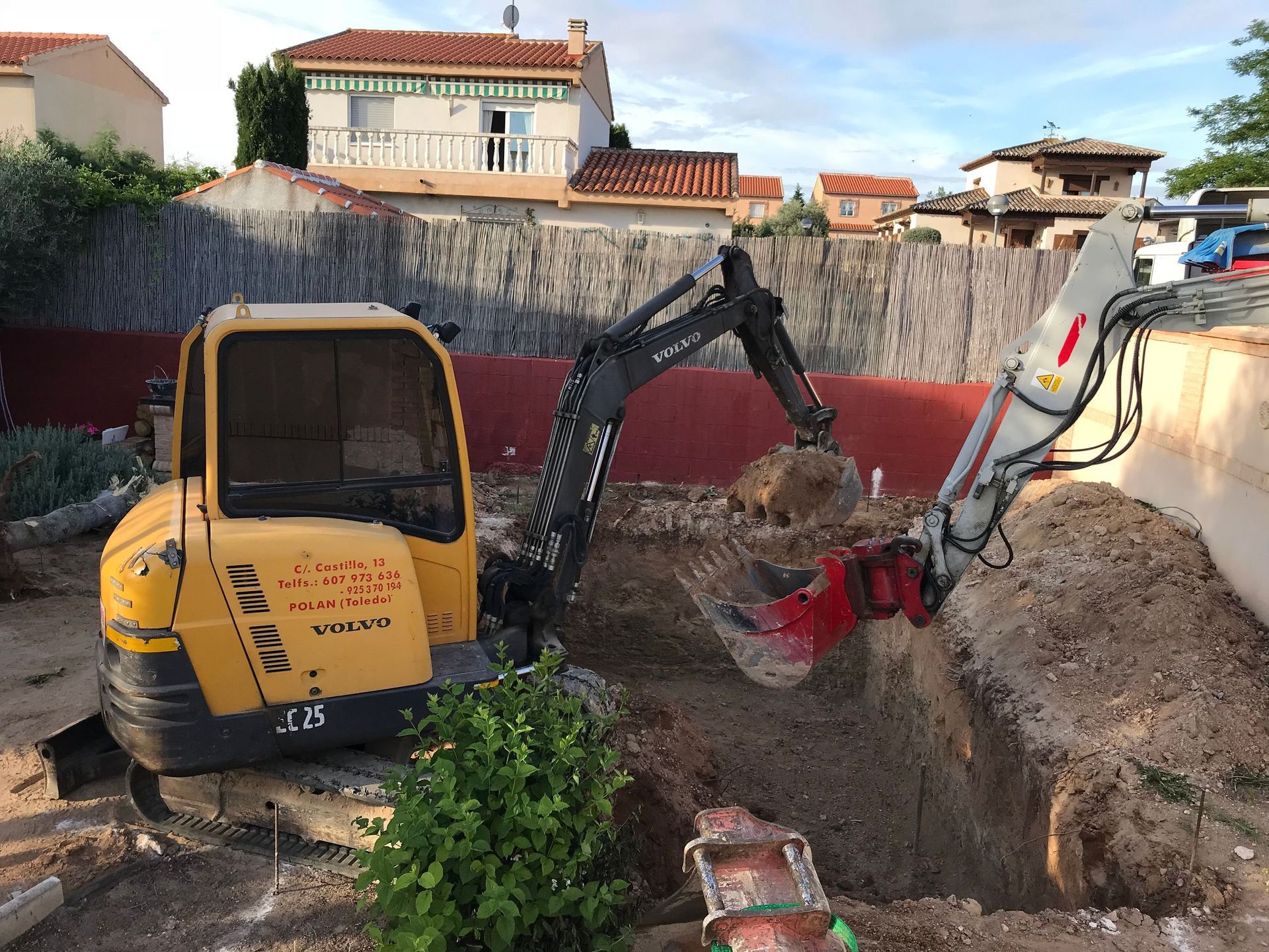 Excavadora amarilla cavando en un patio residencial.