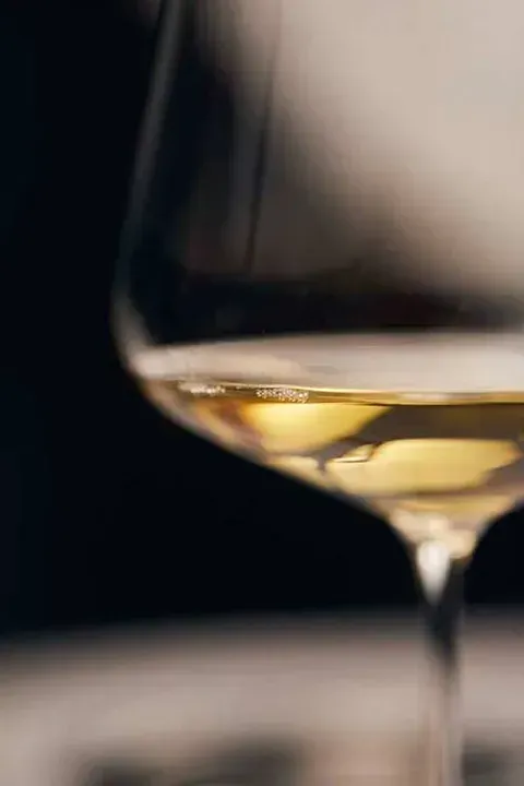 Un primer plano de una copa de vino blanco sobre una mesa.