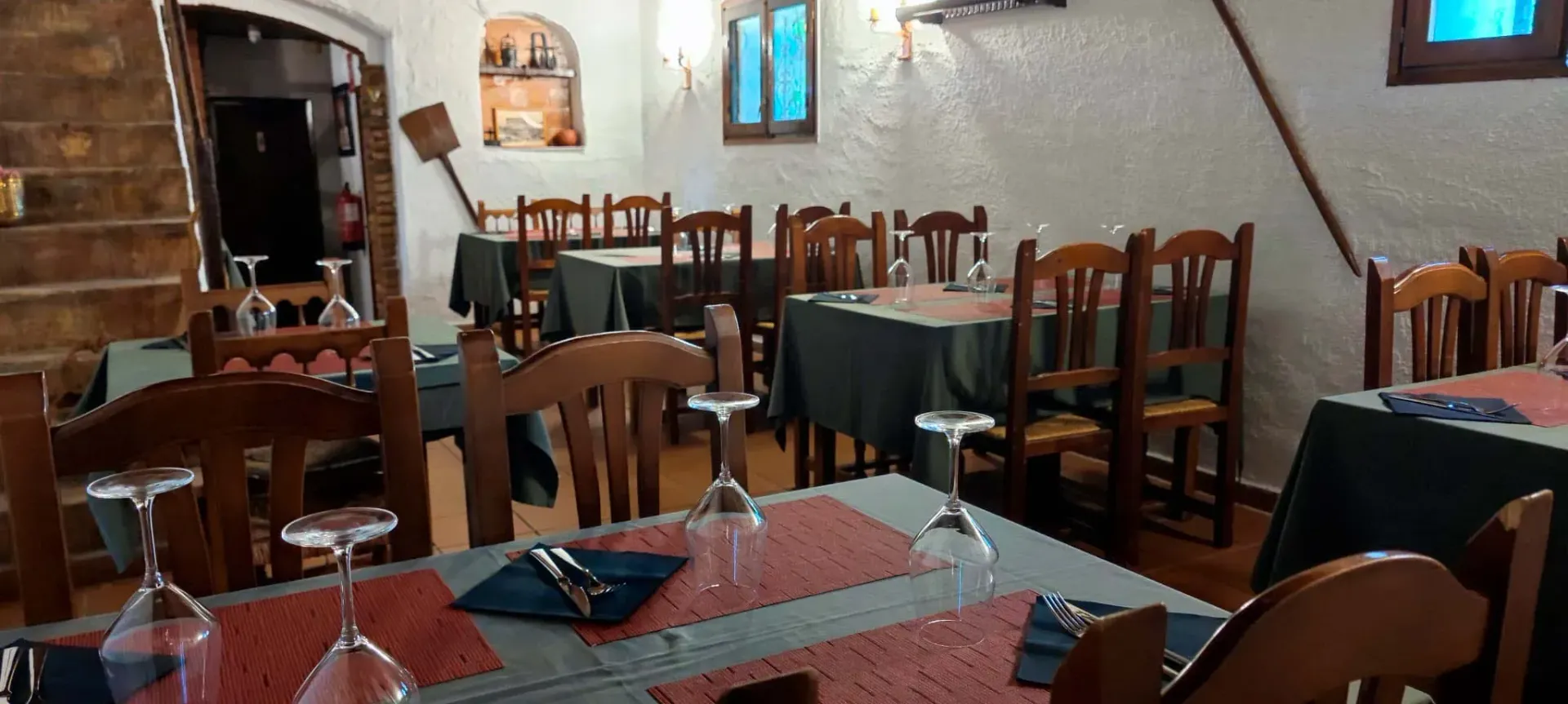 Un restaurante con mesas, sillas y vasos.