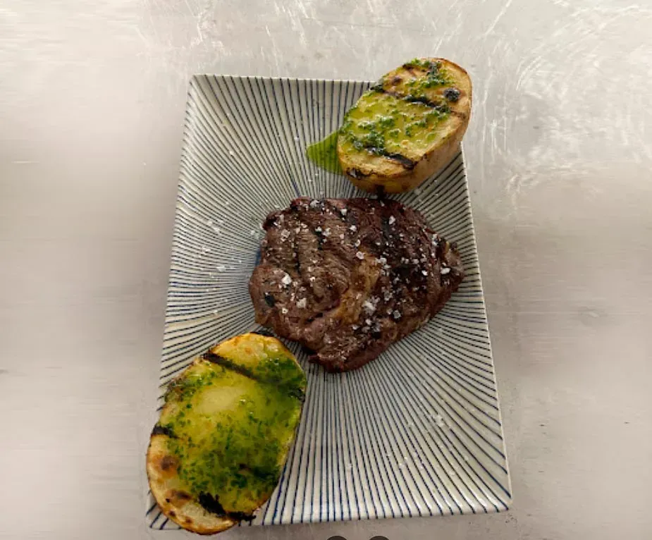 Un plato de comida con carne y patatas en una mesa.