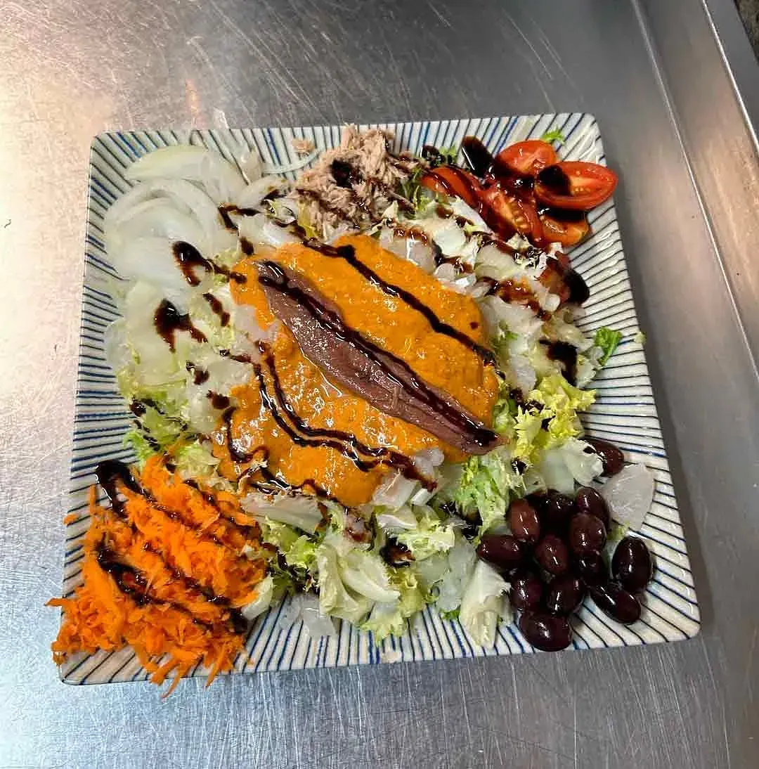Un plato de comida con verduras y carne en una mesa.