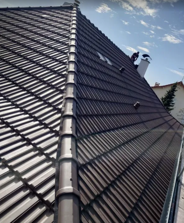 Toiture en tuiles brunes avec gouttière foncée, probablement une maison en cours de travaux de toiture.