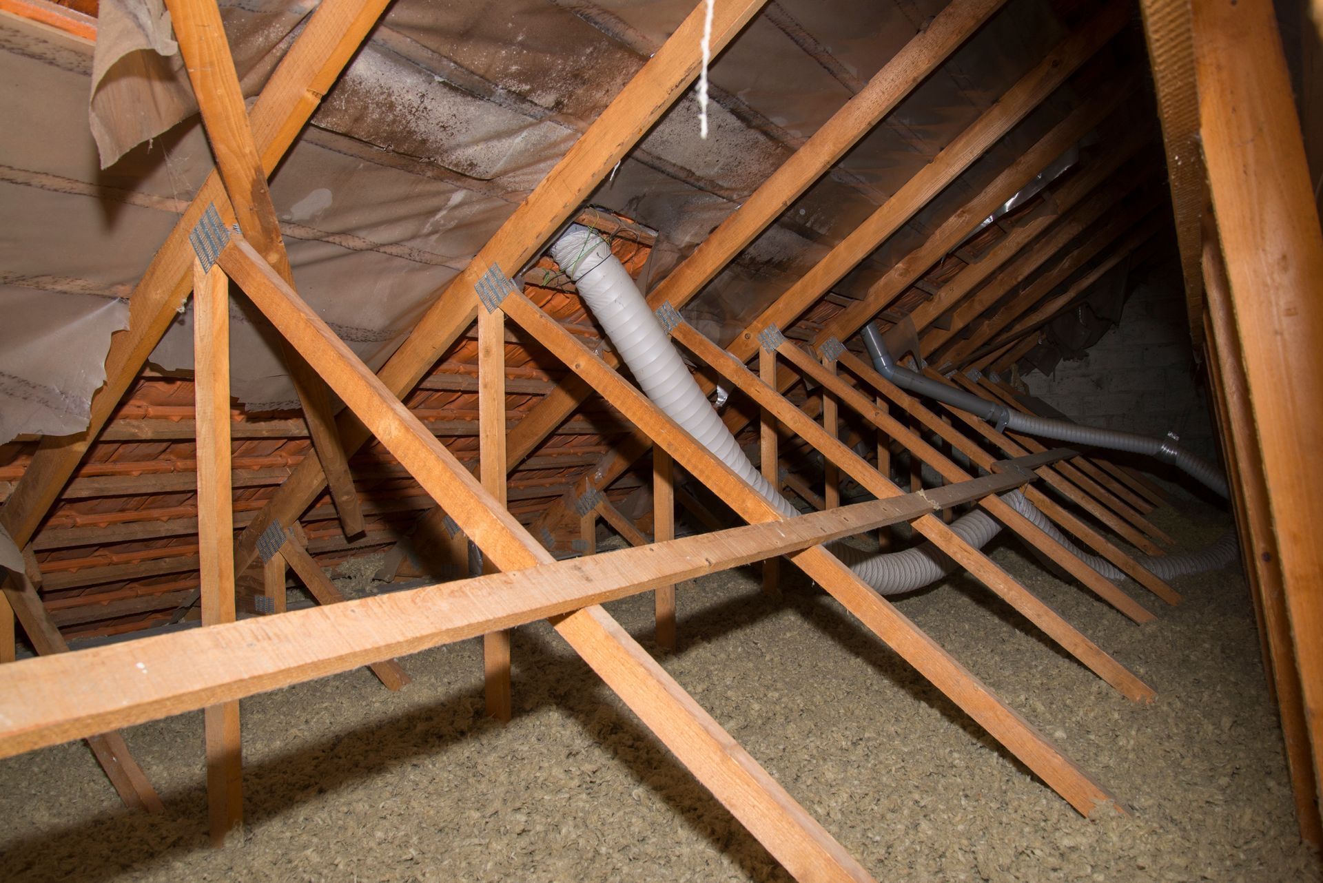 Charpente en bois avec isolation, tuyaux de ventilation et revêtement de toiture apparent.