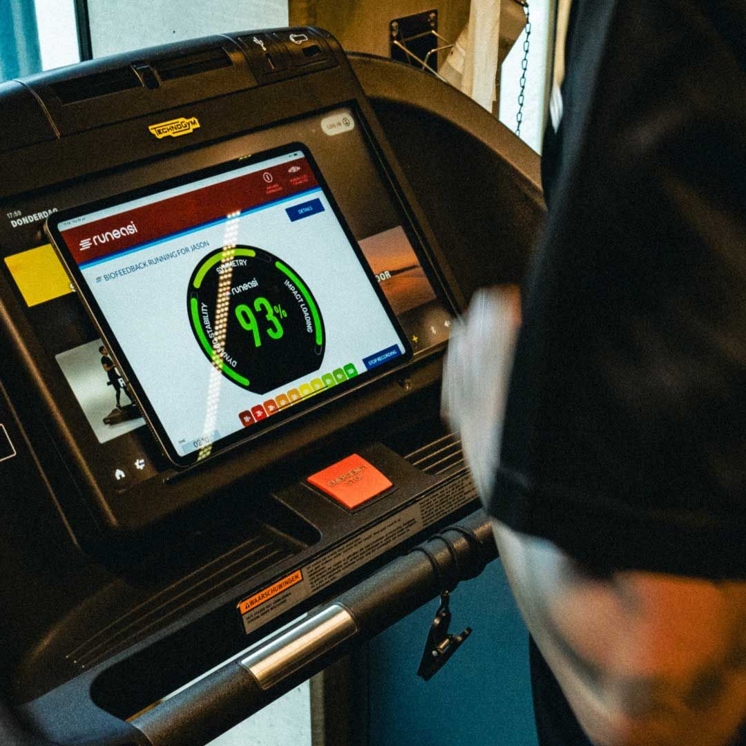 Persona que utiliza una cinta de correr y mira la pantalla de una tableta que muestra una frecuencia cardíaca de 93.