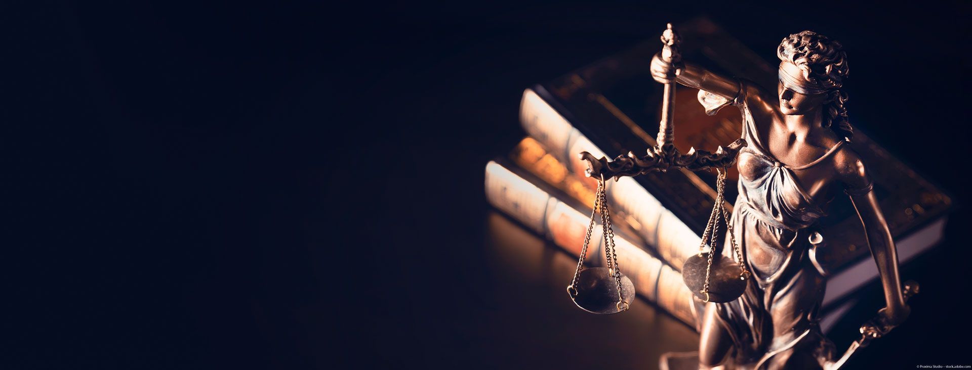 Justitia Figur mit Büchern im Hintergrund