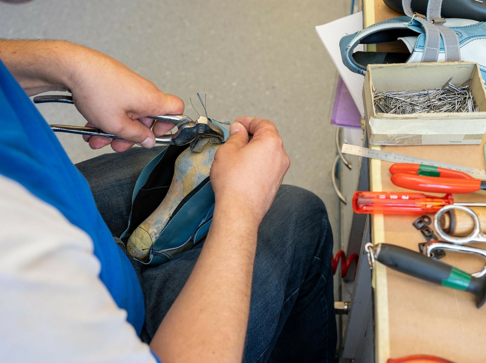 Eine Person bearbeitet einen Schuh mit einer Schere