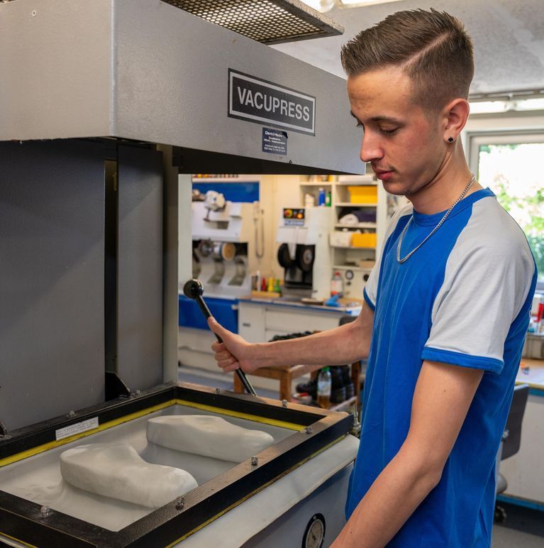 Ein Mann im blauen Hemd arbeitet an einer Vakuumpresse
