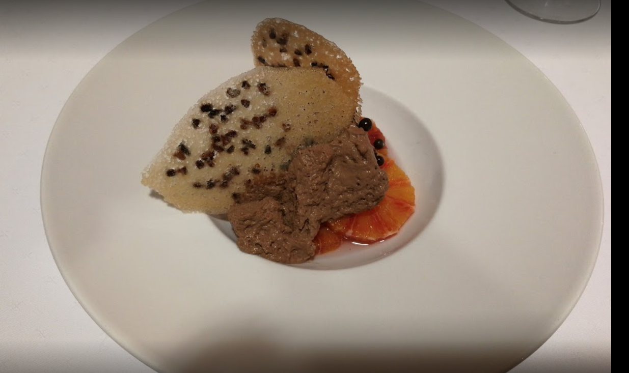 Dessert sur assiette blanche : croustillant beige, crumble au chocolat, tranches d'orange.