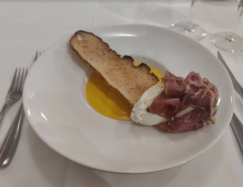 Assiette : pain grillé, sauce jaune, fromage et charcuterie.