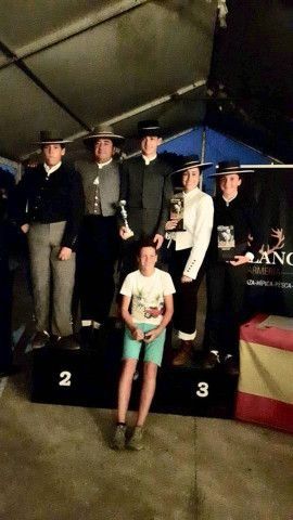 Personas en un podio durante una ceremonia de entrega de premios nocturna, con una persona de pie al frente.