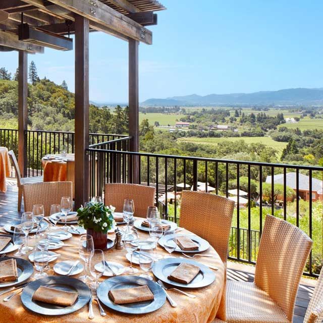 a table with plates and glasses on it with a view of the mountains in the background