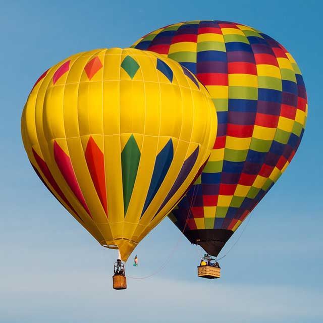 two colorful hot air balloons are flying in the sky