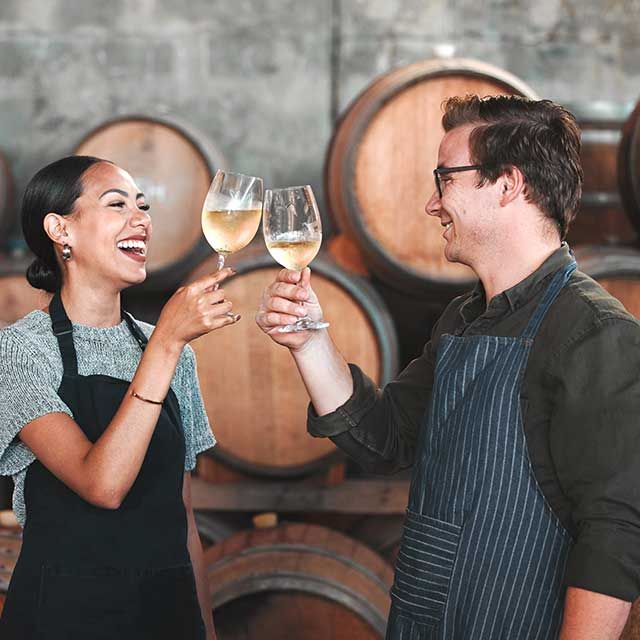 a man and a woman are toasting with wine glasses in a wine cellar .