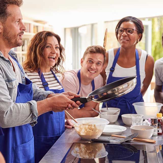 a group of people are standing around a table preparing food .