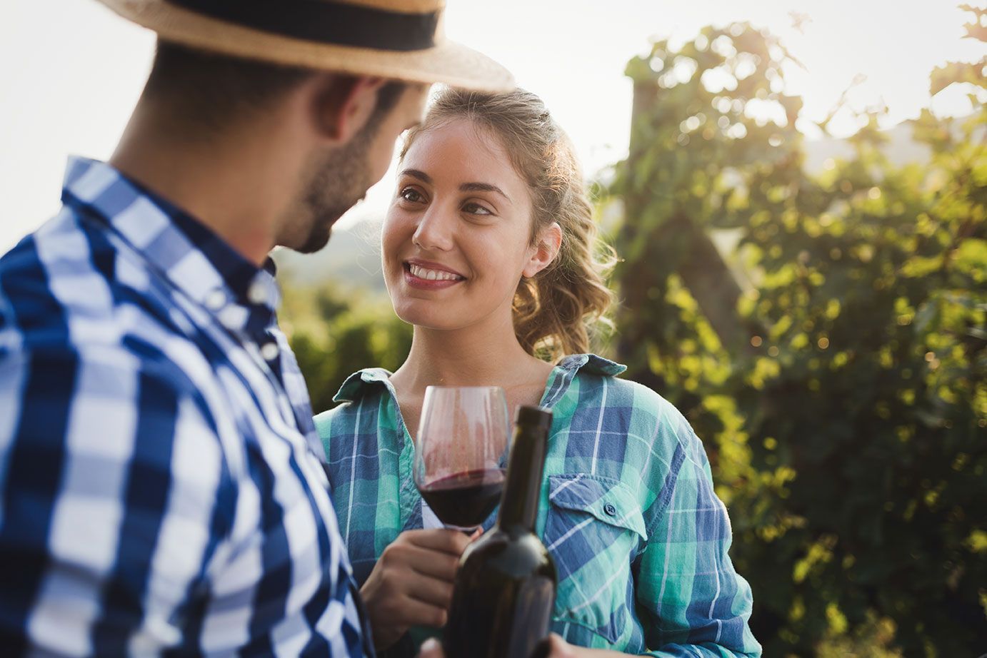 Happy couple enjoying a wine-tasting experience in a sunlit vineyard, embodying a romantic getaway.