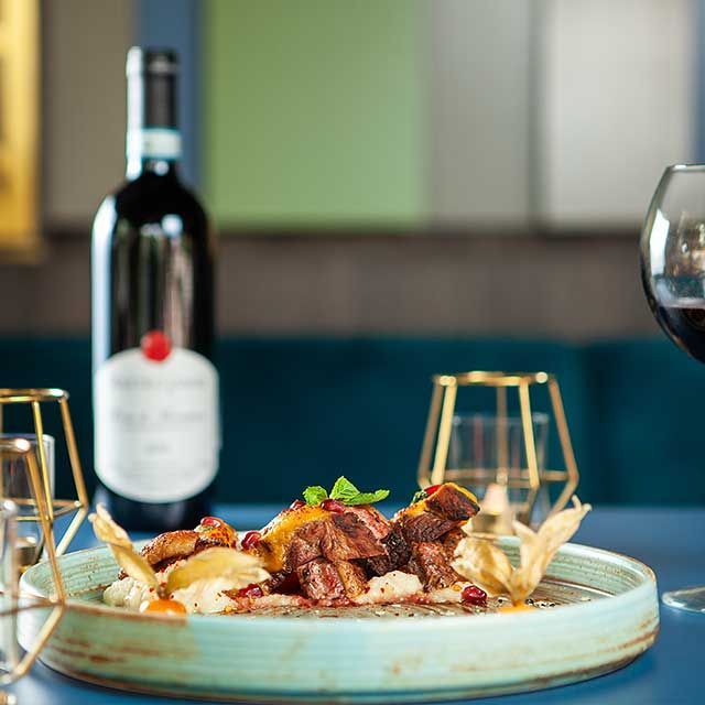 a plate of food with a bottle of wine in the background