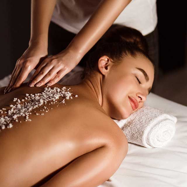 a woman is getting a massage with sea salt on her back .