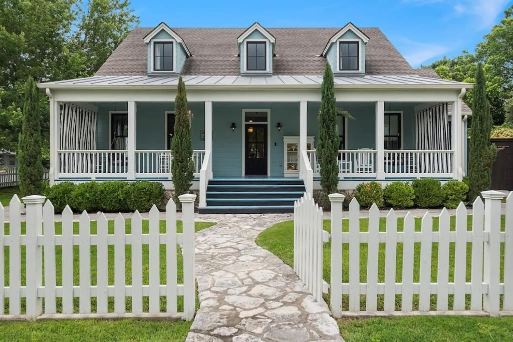 Wasser Haus, a large blue house with a white picket fence in front of it.