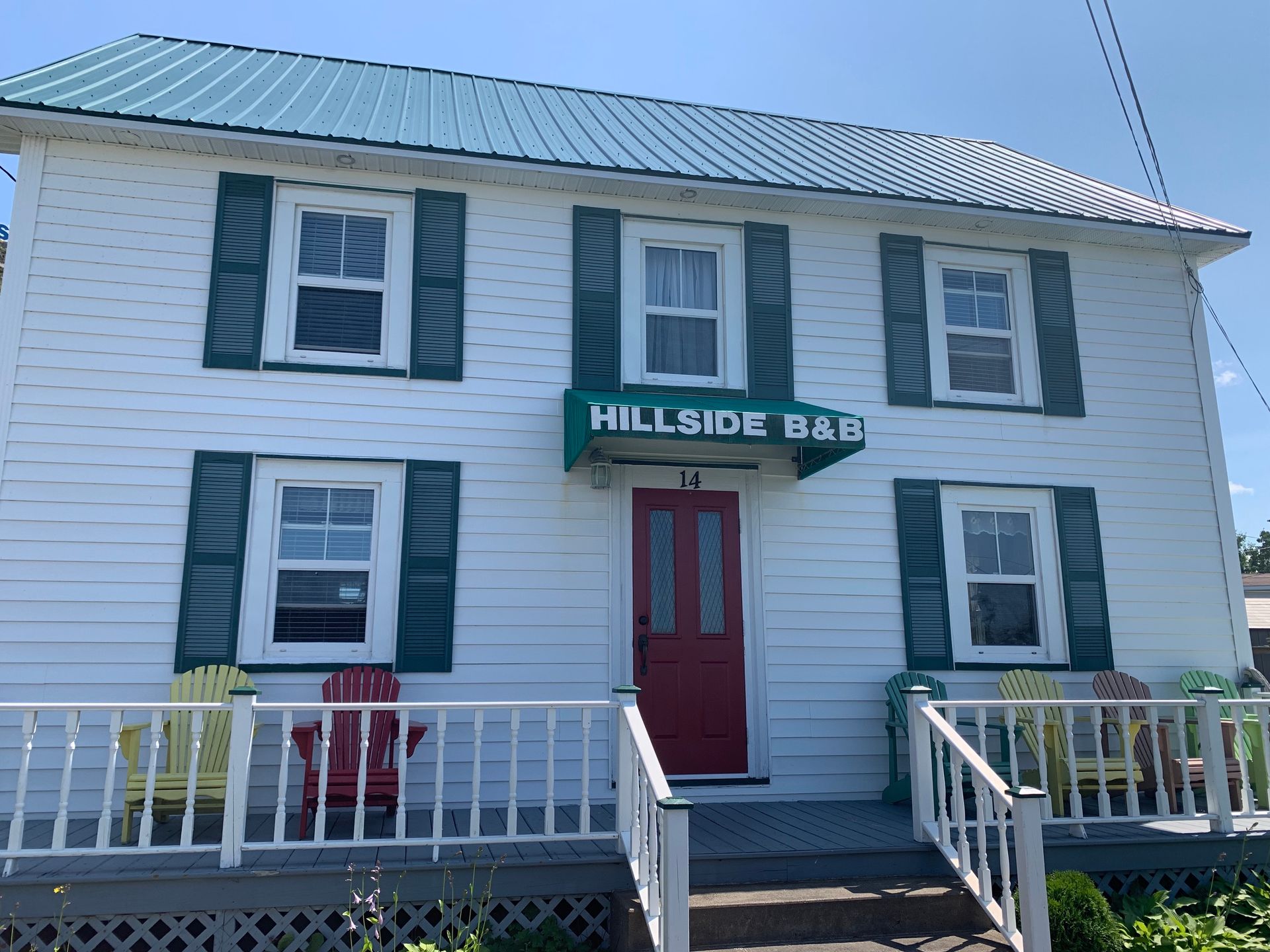 A white house with green shutters and a red door