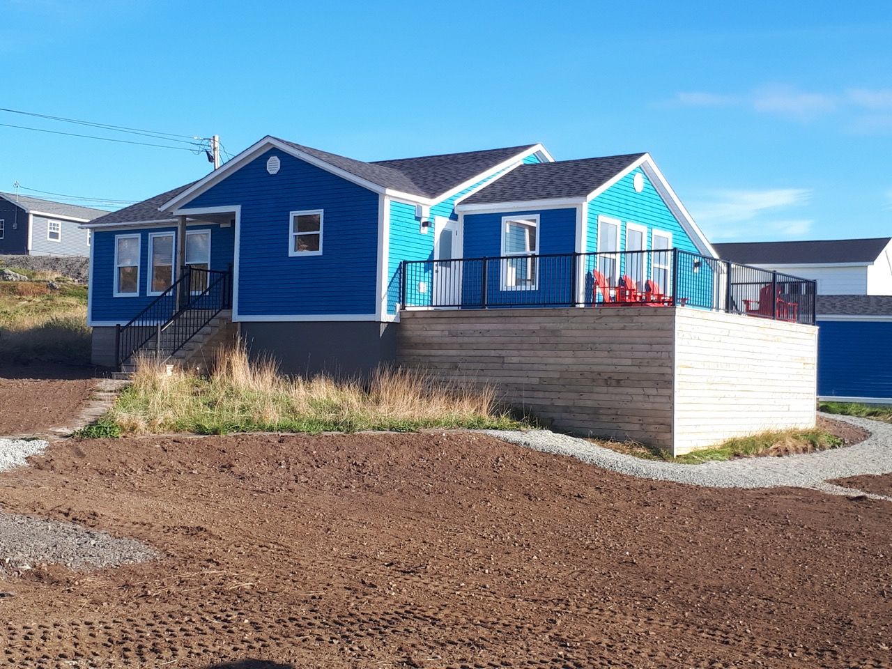 A blue and white house with a large deck in front of it.