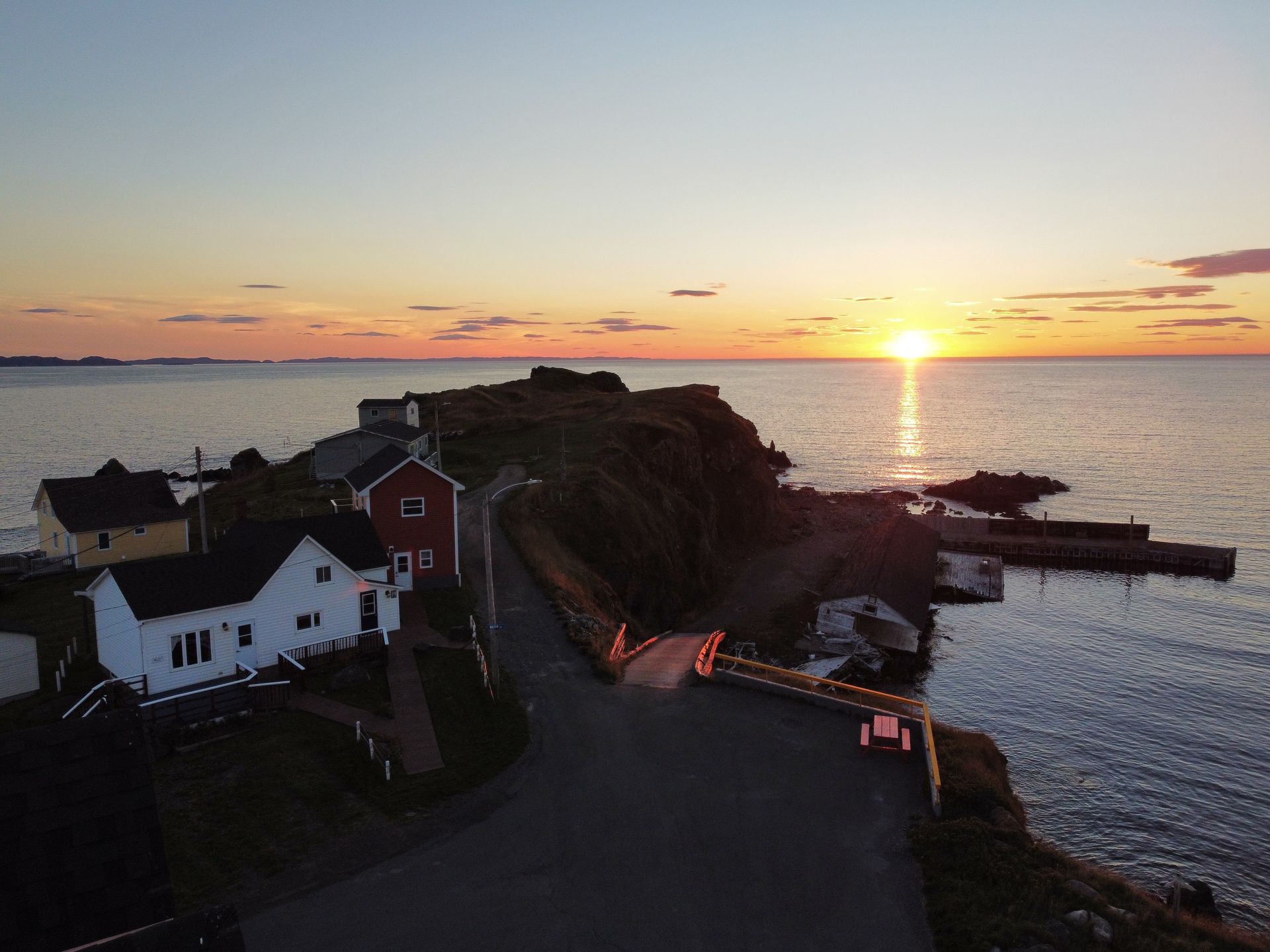 An aerial view of a small town on a cliff overlooking the ocean at sunset