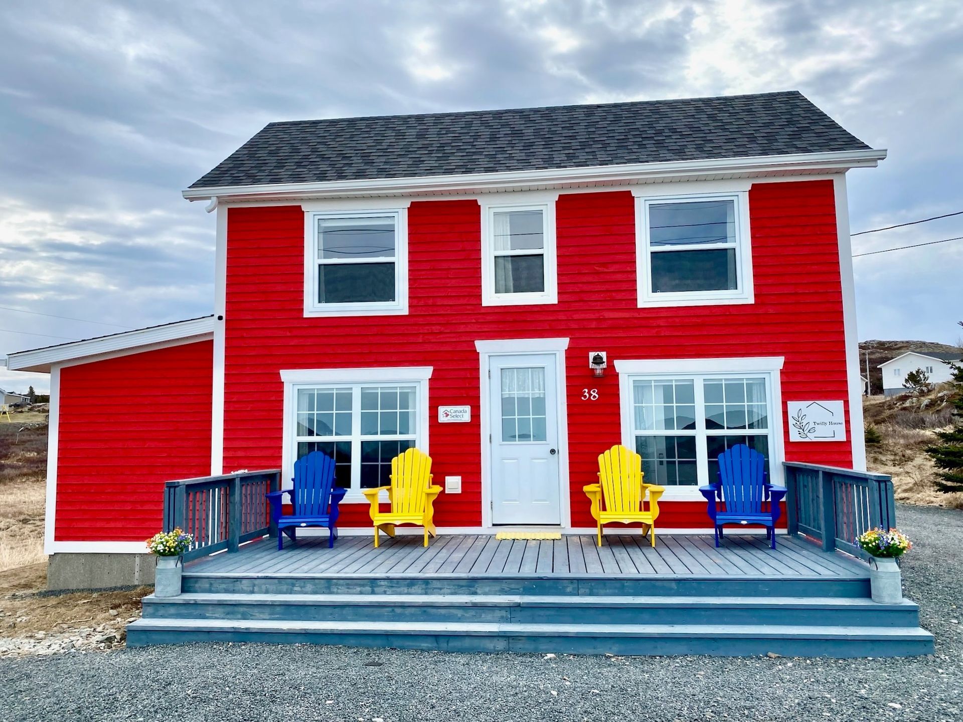 A red house with blue and yellow chairs on the porch