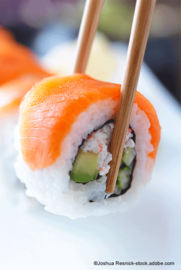 Sushi-Rolle, mit Stäbchen gegessen, mit Lachs, Avocado und Krabbenfleisch.