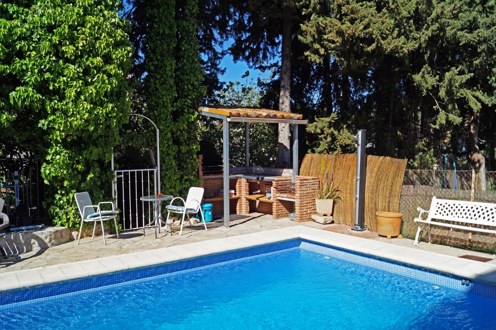 Una gran piscina rodeada de árboles y un cenador.